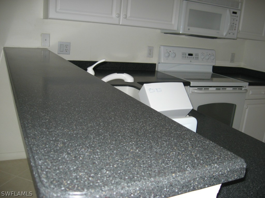 4676 Fairloop Run Lehigh Acres, FL 33973 - Photo 6 of 21 a kitchen with a stove and white cabinets