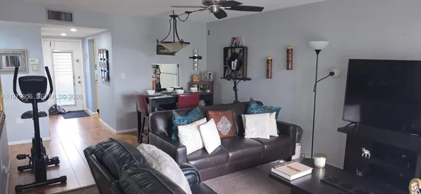 a living room with furniture a flat screen tv and a refrigerator
