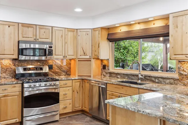 a kitchen with stainless steel appliances granite countertop a stove a sink and a microwave