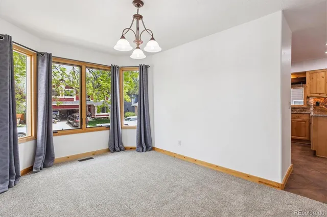 an empty room with chandelier fan and windows