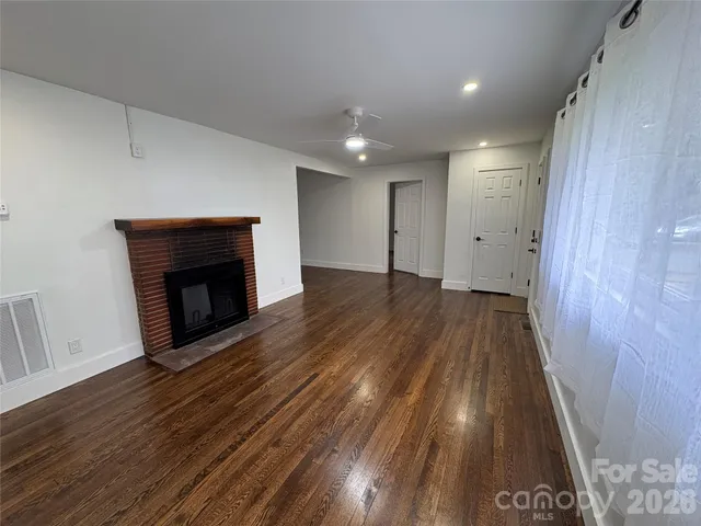 a view of an empty room with wooden floor and a fireplace