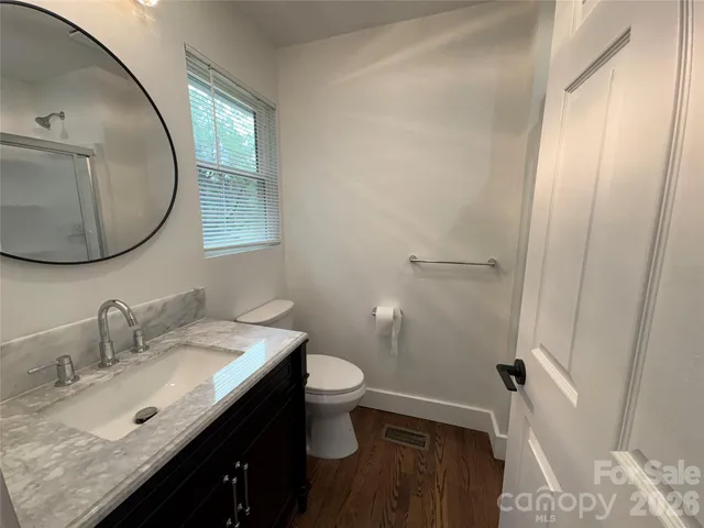 a bathroom with a granite countertop sink toilet and a mirror