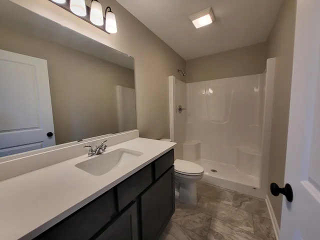 a bathroom with a sink a toilet and shower