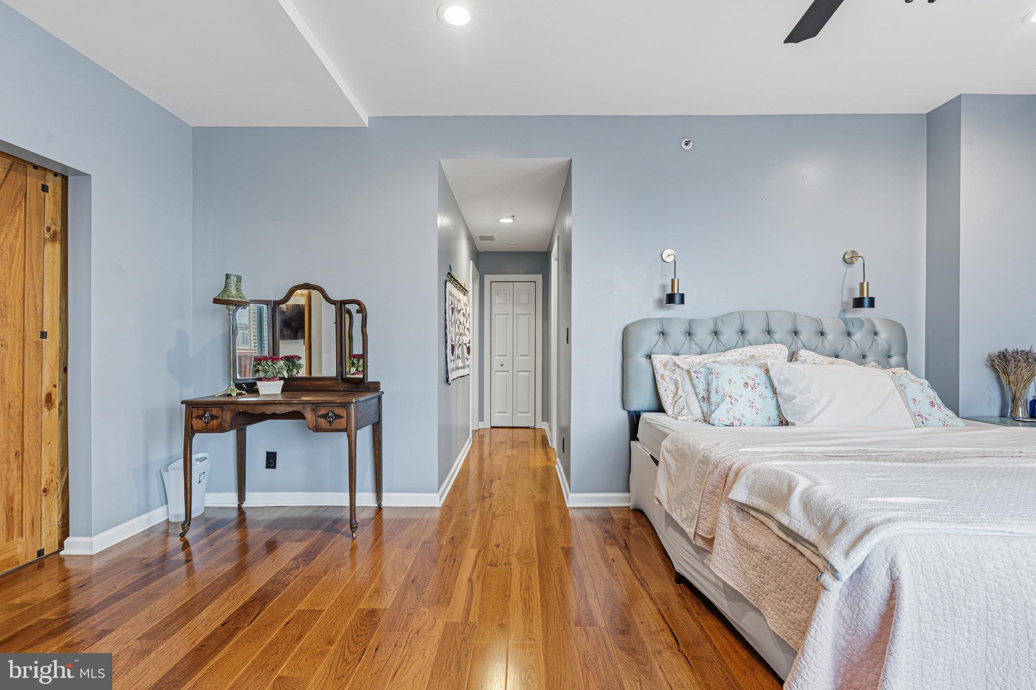 10 East Lee Street, Unit 808 Baltimore, MD 21202 - Photo 17 of 32 a bedroom with a bed and wooden floor