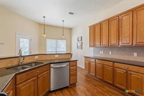 a kitchen with stainless steel appliances granite countertop a sink a stove cabinets and wooden floor
