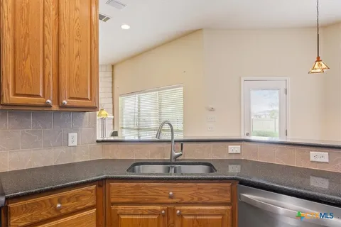 a kitchen with stainless steel appliances granite countertop a sink and a white cabinets