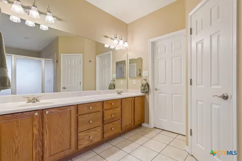 a spacious bathroom with a double vanity sink a mirror and a shower