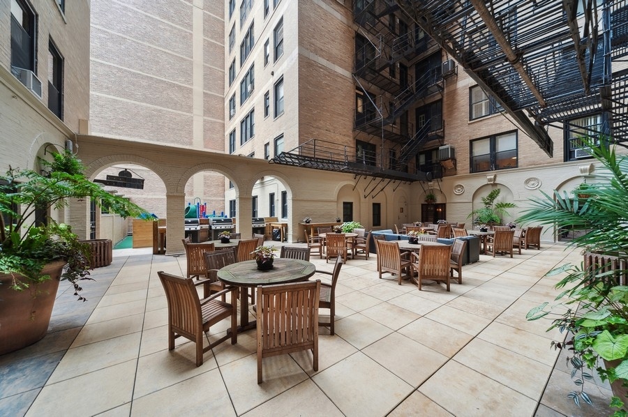 3100 North Sheridan Road, Unit 4B Chicago, IL 60657 - Photo 17 of 19 a view of a patio with dining table and chairs with plants and white umbrellas