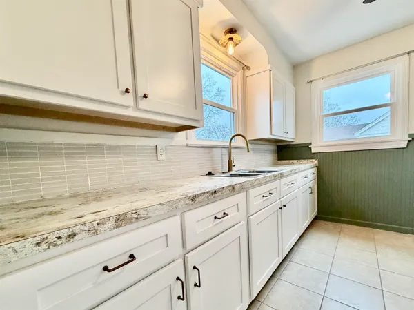 a kitchen with granite countertop white cabinets and sink