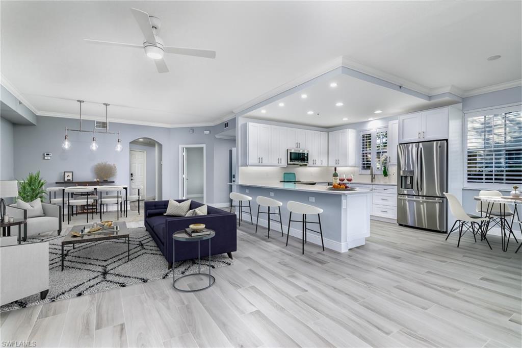 a kitchen with stainless steel appliances kitchen island granite countertop a refrigerator oven a dining table and chairs with wooden floor