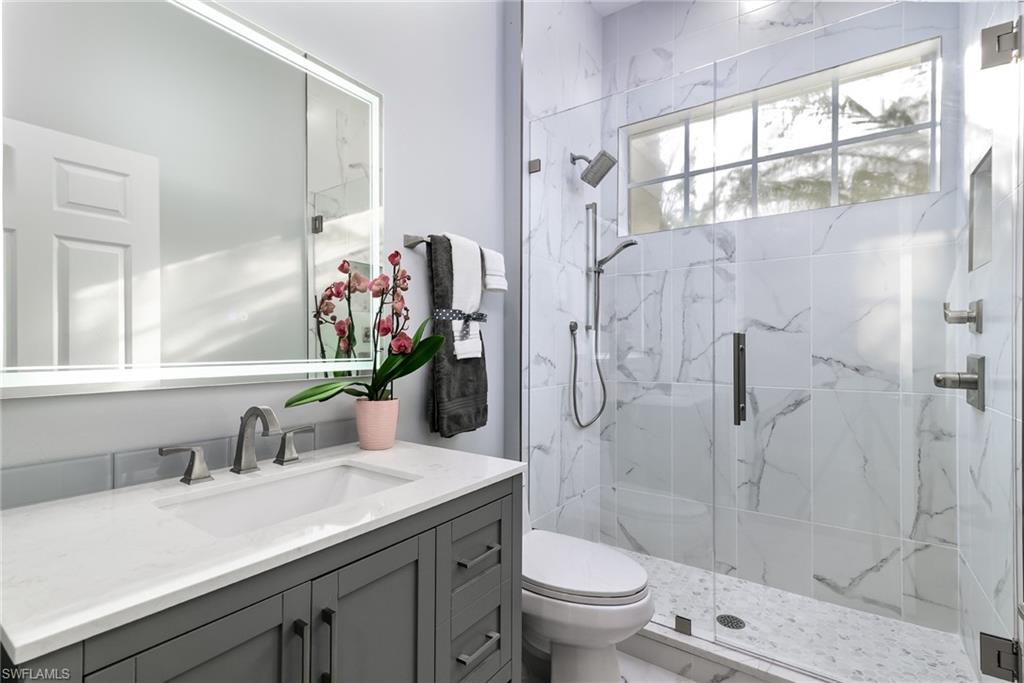 2090 Aberdeen Lane, Unit 101 Naples, FL 34109 - Photo 13 of 37 a bathroom with a granite countertop sink toilet and shower