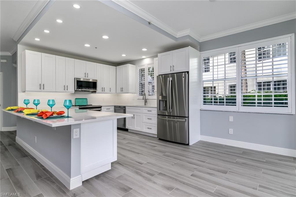 2090 Aberdeen Lane, Unit 101 Naples, FL 34109 - Photo 4 of 37 a kitchen with refrigerator cabinets and wooden floor
