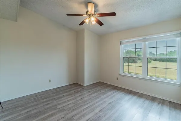 a view of empty room with wooden floor and fan