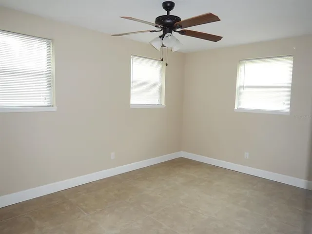 an empty room with a window and a fan