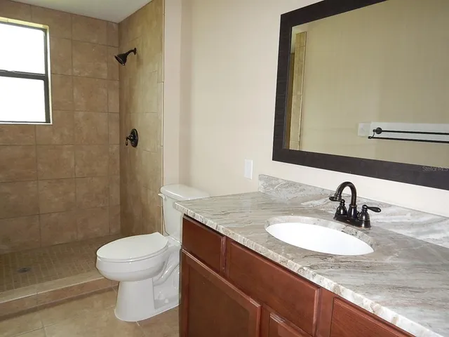 a bathroom with a granite countertop sink toilet and shower