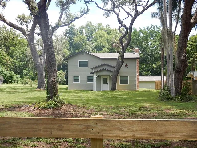 a white house that has a tree in front of it