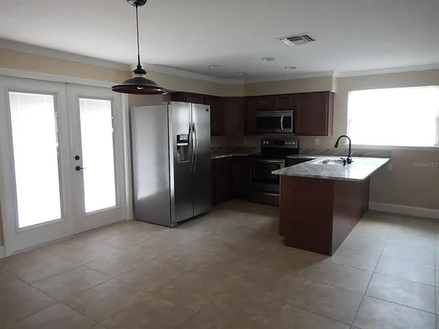 a kitchen with stainless steel appliances granite countertop a refrigerator a sink a stove and a microwave