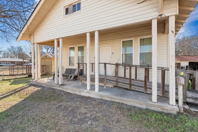 a view of a house with wooden deck and a floor to ceiling window