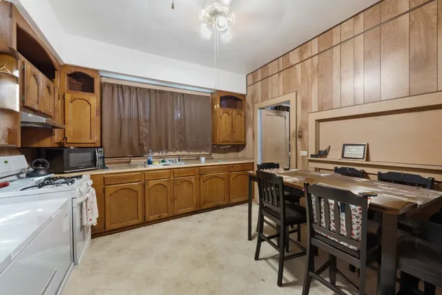 a kitchen with stainless steel appliances granite countertop a stove a sink dishwasher and cabinets with wooden chairs