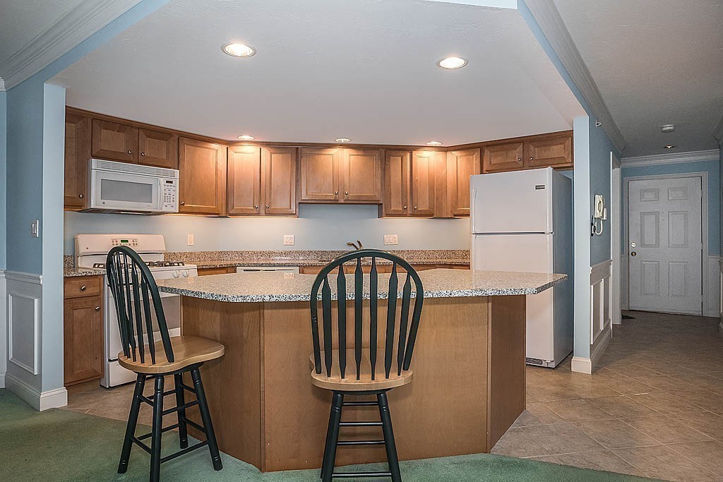 5 Mission Road, Unit 304 Chelmsford, MA 01863 - Photo 3 of 30 a kitchen with a table chairs refrigerator and cabinets