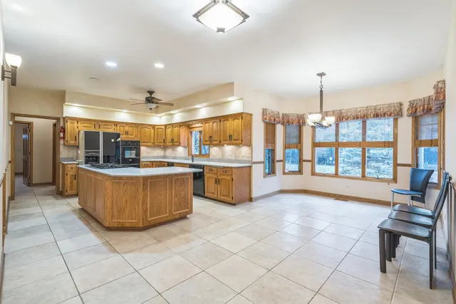a room with stainless steel appliances kitchen island granite countertop lots of counter space and windows