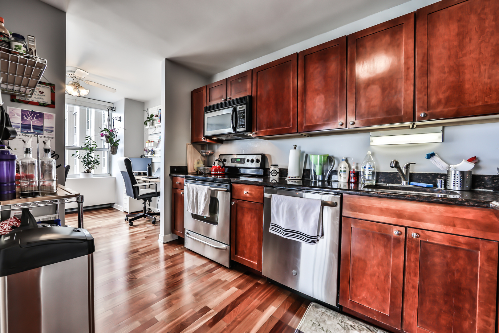 655 West Irving Park Road, Unit 3810 Chicago, IL 60613 - Photo 12 of 26 a kitchen with stainless steel appliances granite countertop wooden cabinets a stove top oven a sink and dishwasher with wooden floor