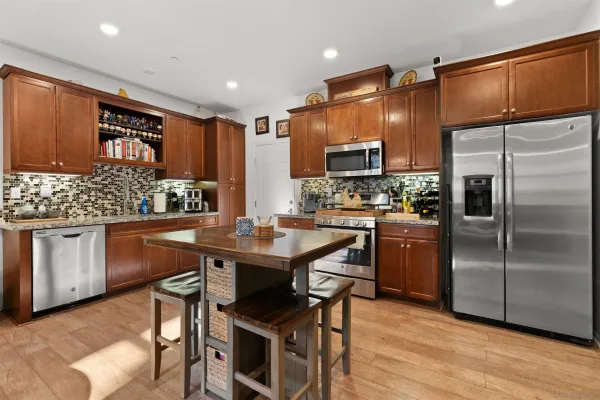 a kitchen with stainless steel appliances a table chairs and a refrigerator