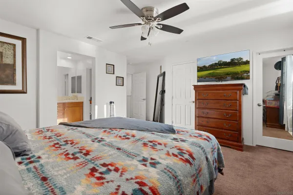 a bedroom with a bed a dresser and a chandelier