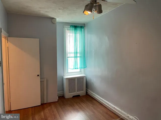 an empty room with a window and wooden floor