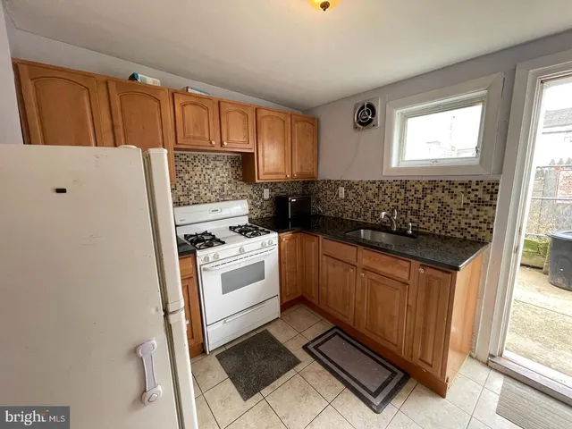 a kitchen with granite countertop a refrigerator sink and cabinets