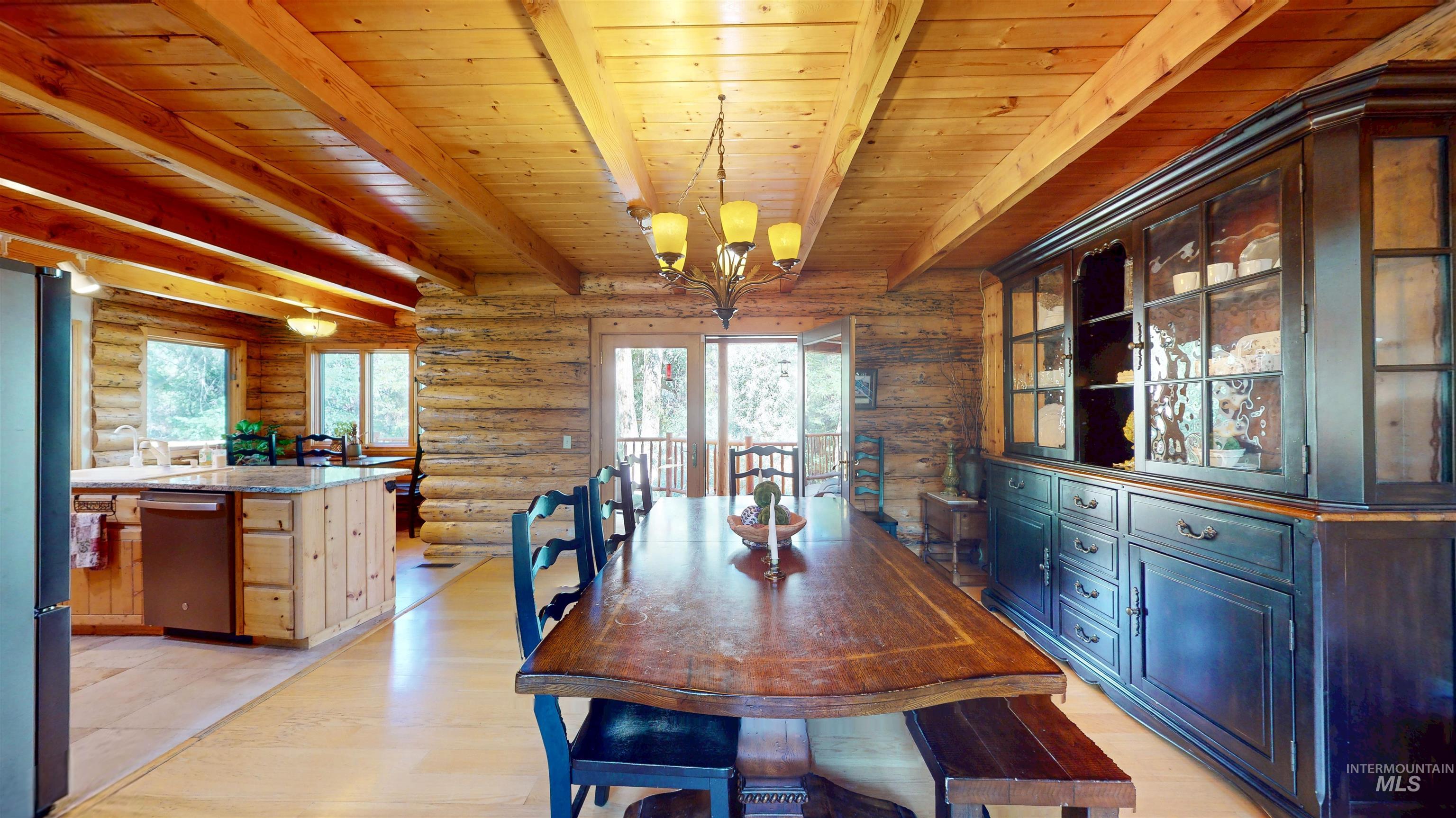 1314 River Road Buhl, ID 83316 - Photo 11 of 45 Dining room featuring log walls, a wooden ceiling with exposed beams, a chandelier, and light wood-style flooring