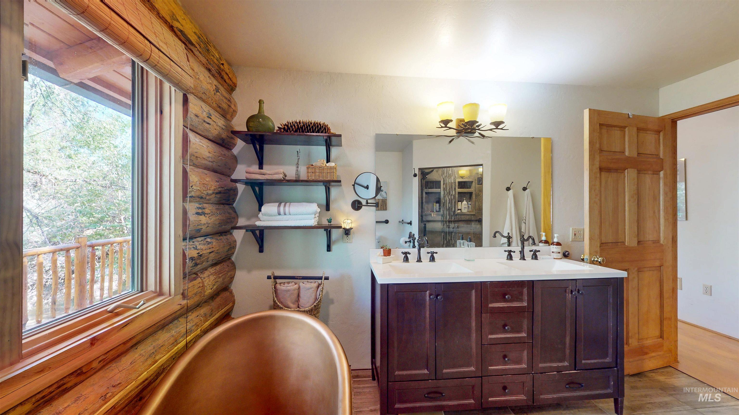 1314 River Road Buhl, ID 83316 - Photo 18 of 45 Full bathroom with healthy amount of natural light, a soaking tub, double vanity, rustic walls, and wood finished floors