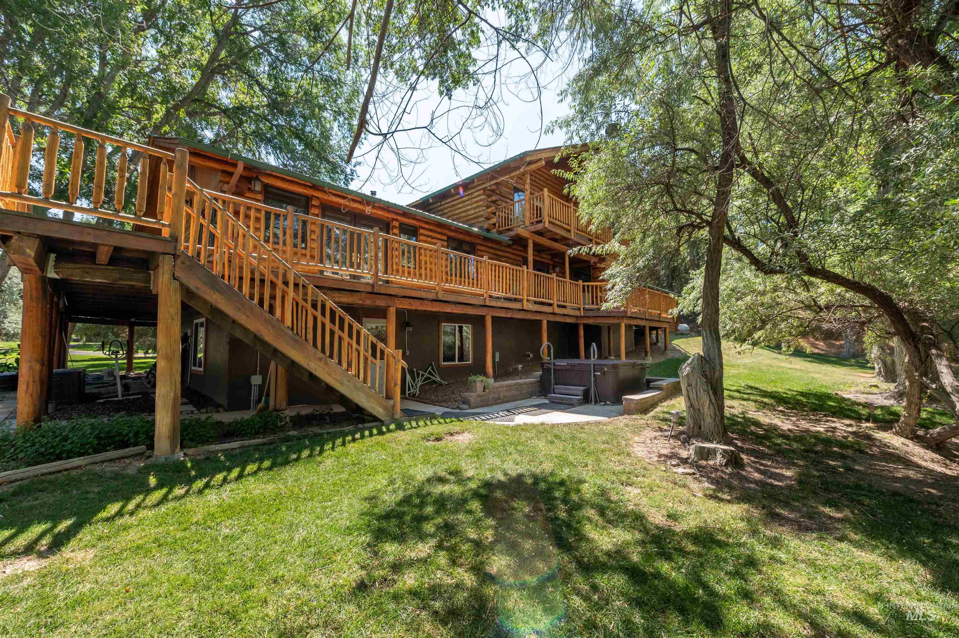 1314 River Road Buhl, ID 83316 - Photo 5 of 45 Back of property with a hot tub, log siding, a wooden deck, a yard, and stairway