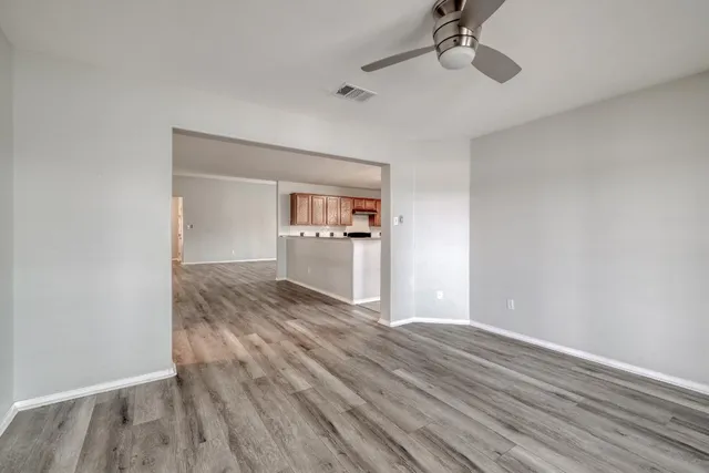 a kitchen with stainless steel appliances granite countertop white cabinets a sink a stove a refrigerator with grey cabinets and wooden floor