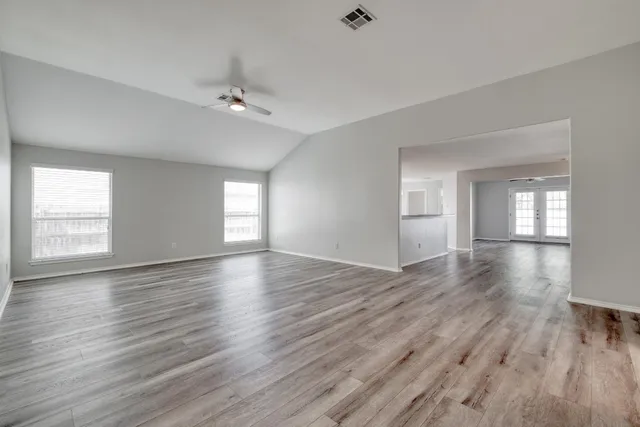 a view of empty room with wooden floor and fan