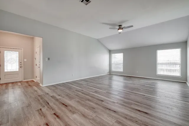 a view of empty room with wooden floor
