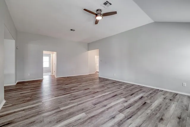 a view of empty room with wooden floor and fan