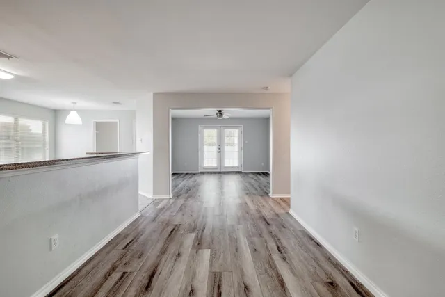 a view of a room with wooden floor a ceiling fan and windows