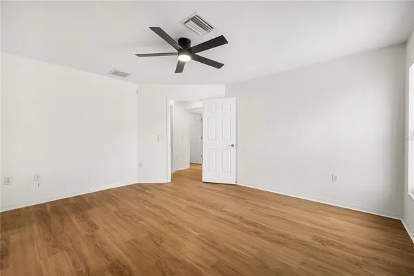 an empty room with wooden floor and ceiling fan