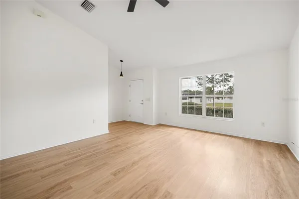 a view of an empty room with a window and wooden floor