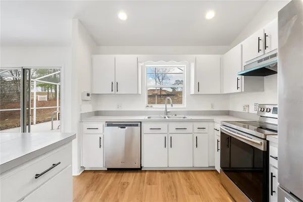 a kitchen with stainless steel appliances granite countertop a sink cabinets and wooden floor