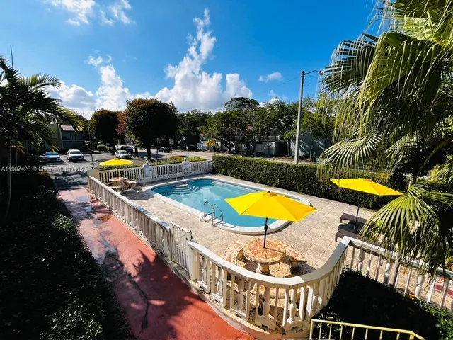 a view of a swimming pool with lounge chair and palm tree