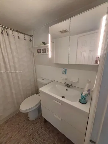 a bathroom with a sink a toilet and shower curtain