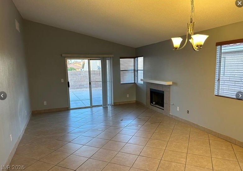 7652 Kalmalii Avenue Las Vegas, NV 89147 - Photo 2 of 9 A well-lit living area features tiled flooring, a corner fireplace, and direct patio access.