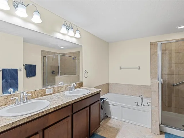 a bathroom with a granite countertop tub a double vanity sink and a mirror
