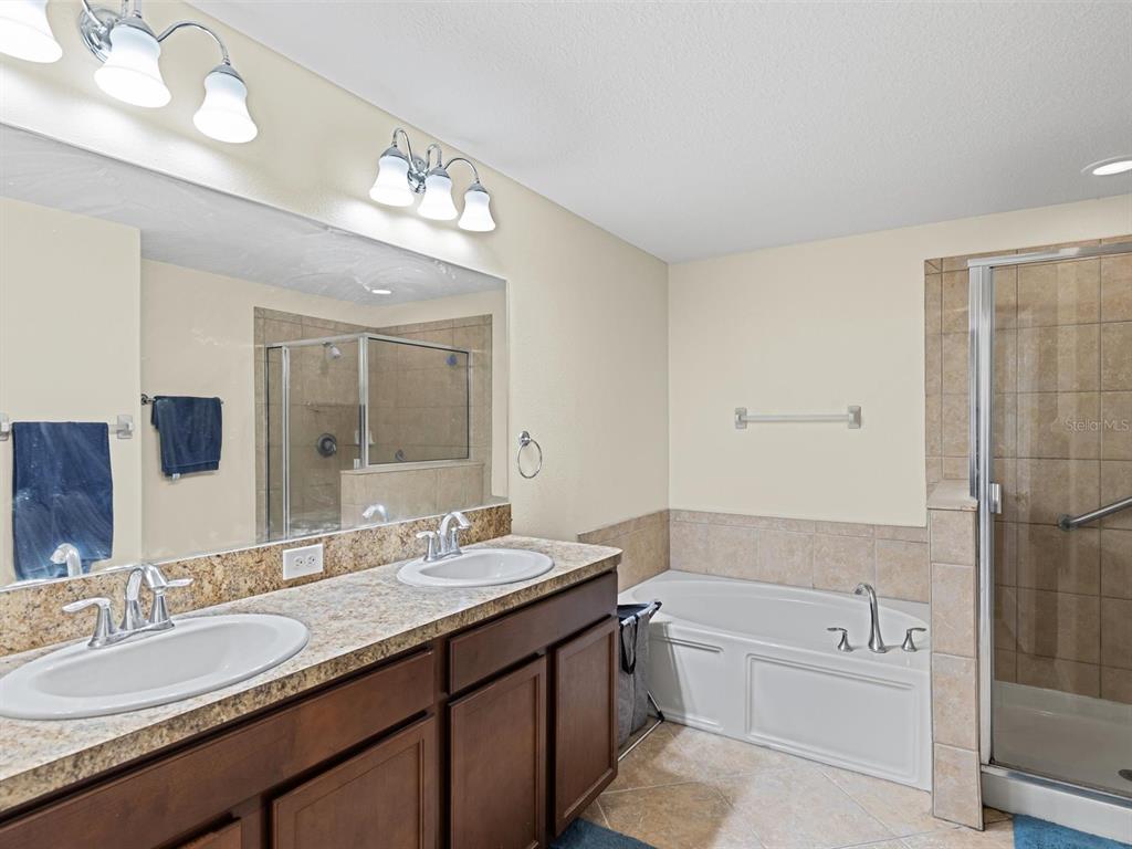 9588 Trumpet Vine Loop Trinity, FL 34655 - Photo 20 of 49 a bathroom with a granite countertop tub a double vanity sink and a mirror