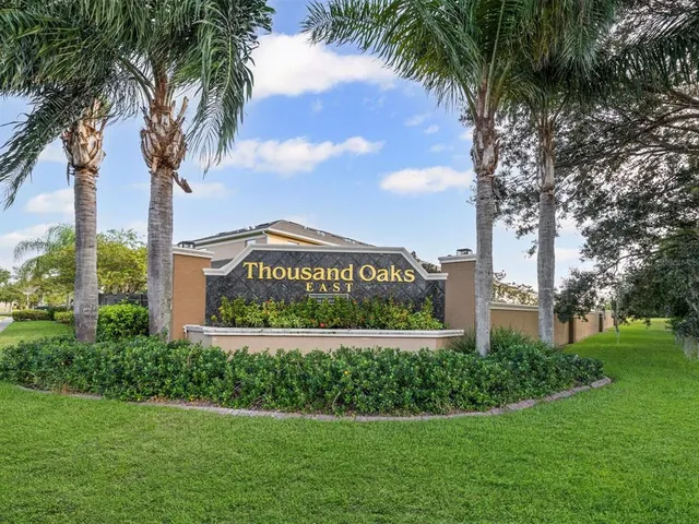a sign board with a park and trees