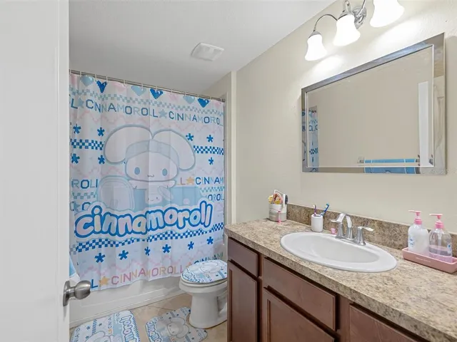 a bathroom with a granite countertop toilet sink mirror and shower