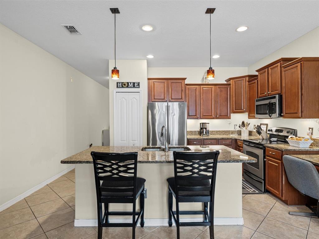 9588 Trumpet Vine Loop Trinity, FL 34655 - Photo 8 of 49 a kitchen with stainless steel appliances granite countertop a stove a refrigerator a sink a dining table and chairs