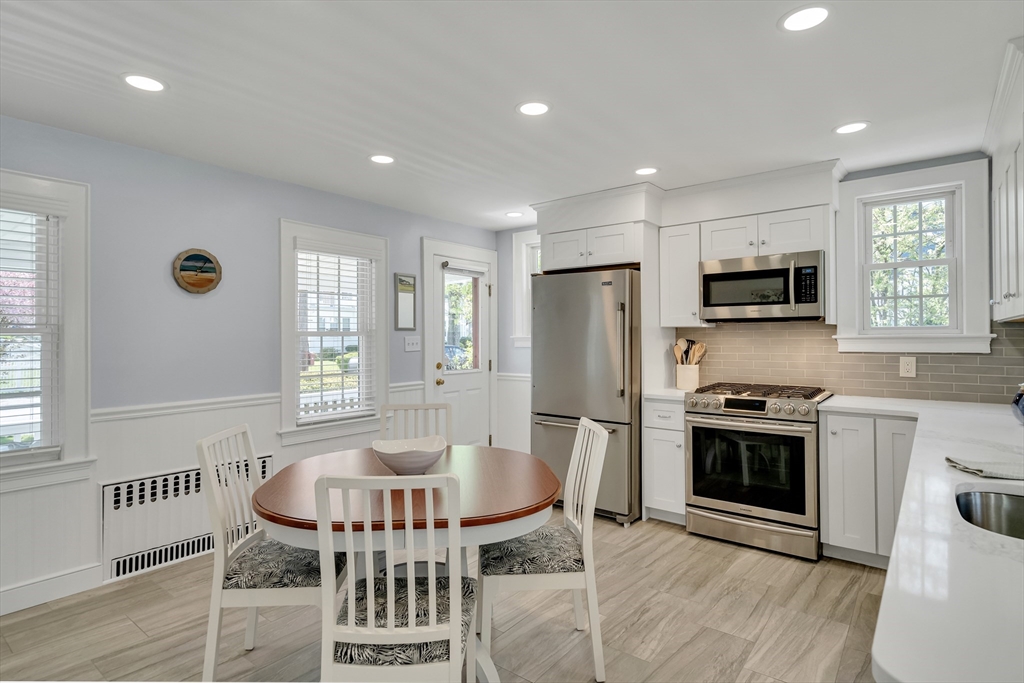 90 Governors Road Milton, MA 02186 - Photo 6 of 28 a kitchen with stainless steel appliances granite countertop a stove a sink a refrigerator a microwave a dining table and chairs